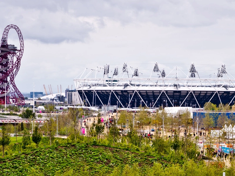 Sports stadium exterior surrounded by fun fair and rollercoaster