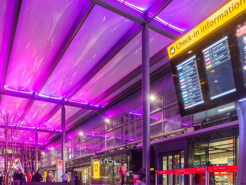 Airport terminal with purple ceiling and check-in information board